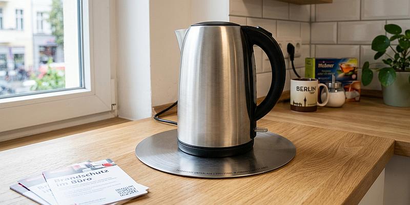 Bild: Feuerfeste Brandschutzunterlage aus Edelstahl unter einem Wasserkocher